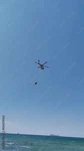 Firefighting helicopter takes water from the sea. vertical video for social media.