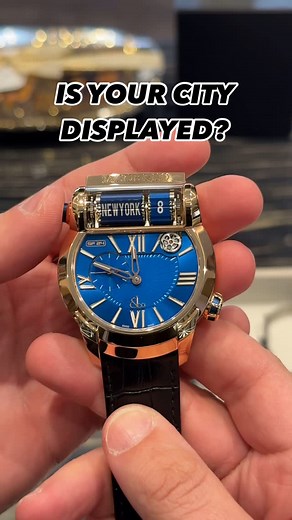 WRIST ENTHUSIAST on Instagram: "The @jacobandco Epic SF24 is one of the more interesting takes on a world timer. The “SF” stands for Split Flap, referring to the display at the top of the case—designed to mimic the old airport departure boards. With the push of a button, it flips through 24 time zones, adding a tactile and mechanical element to something usually handled with a static dial or rotating bezel. In rose gold with a blue dial, it has a strong presence, but the real focus is on the com