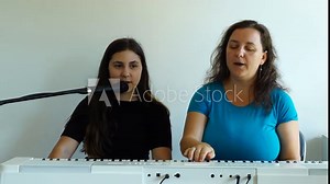 Teenager girl has a vocal lesson with teacher playing piano