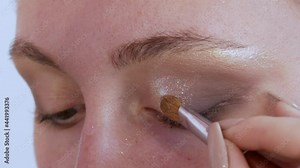 Beautiful shiny shadows are applied with a special brush on the eyelid of the model. The process of bright evening make-up close up view Stock Video