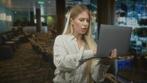 clip-4019514197-woman-blonde-holding-laptop-typing-one-hand