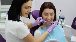Dentist selecting tooth color from special scale. Girl patient and dentures teeth shade selection