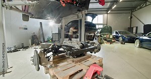 Mechanic working on repairing an electric vehicle in a modern auto workshop, highlighting EV maintenance and service procedures. EV repair concept. Auto Service, Electric Car Battery Handling.