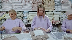 Textile workers at workplace packing the finished products of the clothing. Media. Packaging of fabrics for transportation.