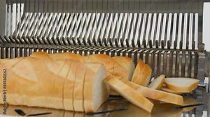 Bread slicer in factory. Sharp knives cuts bread