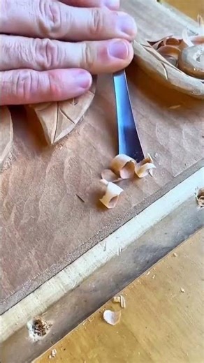 carving intricate patterns on wood using a metal chisel while small shavings fall away