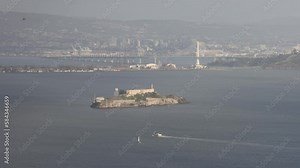 Ferry cruises by Alcatraz Island in San Francisco Bay on hazy day