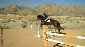 Epic shot of jockey jumping over fence on horse