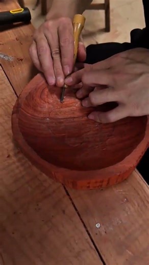 carving a lotus pattern on a wooden bowl with a chisel tool carefully for decorative art creation
