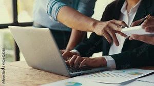 Business manager assisting an employee by pointing at a laptop screen while discussing a task and analyzing data