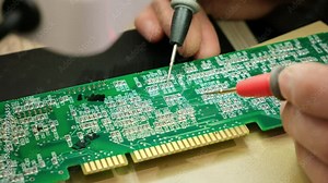 The Engineer Technician looking through the printed circuit board of an electronic device under a microscope. Electronic equipment repair shop.