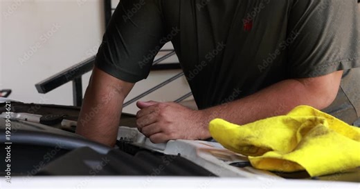 Close up male hand pulling the engine oil dipstick to check lubricant level inside a car engine bay. Driver doing routine auto maintenance and vehicle safety check before road trip. 4K video.