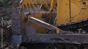 Crawler bulldozer working on construction site or quarry. Mining machinery moving soil. Dozer is pushing dirt. Yellow excavator on new construction site. Drainage of swamps. Peat mining.