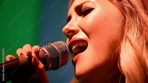 Woman singing into microphone against green screen