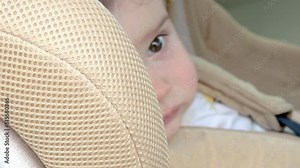 car seat and children's safety concept.baby is sitting in auto chair and crying,nervous,hysteric,agitated,refuse to stay.handling a stubborn child. blurry toddler face,modern car interior.