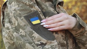 Close up velcro patch, flag of Ukraine on military uniform soldiers arm. Female servicewoman dressed in the camouflage, symbol of independence. Armed Forces of Ukraine. Woman serving in ukrainian army