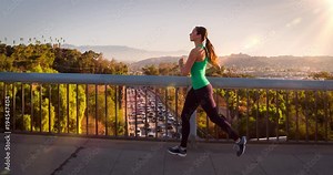 Athletic Woman Working Out. Jogging across a bridge. Trees, Sun and city can be seen in the background. Slow Motion. Stock Video
