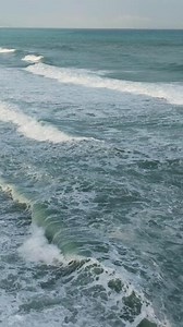 Aerial view capturing wind waves crashing fluidly on a freezing ocean beach
