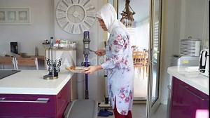 Middle-aged muslim woman does housework Kitchen cleaning home wearing hijab headscarf. Islamic female washing home dishes. Housewife daily household life routine.