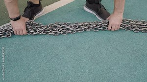 Chain to increase the load on the athlete's neck. Male bodybuilder with sculpted muscular body posing with a chain around his neck. The lifter puts the weight chain around the neck.