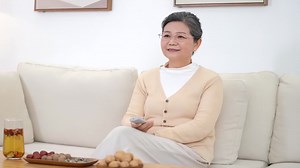 Happy middle aged aunt and grandma woman holding remote control, watching tv movie on comfortable sofa at home and pressing the remote control to change channels | Premium Stock Video Footage