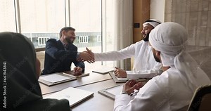 Multicultural business partners shake hands at meeting in boardroom. Company executives and clients, investors make deal, accomplish talk, shake hands express recognition for effective negotiation