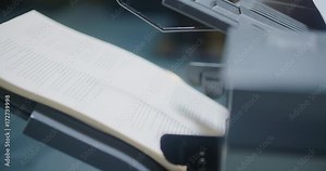 Printer Side Profile Spinning Out Book Paper Pages. a close up view from right to left of a large printer spitting out paper from the side profile