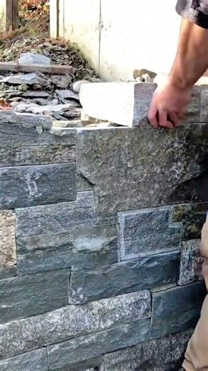 Carefully placing a stone block to build a sturdy and seamless masonry wall