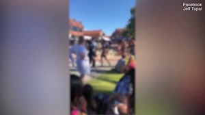 Two girls punch and slap each other in front of shocked families