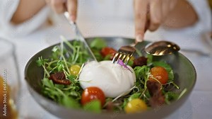 Young woman mixing burrata salad at the restaurant