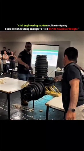 axisrnx18M on Instagram: "This video showcases a remarkable feat of structural engineering where a group of civil engineering students at a university in Brazil (as indicated by the "Engenharia Civil" text on a shirt) test a scale model bridge. The bridge, constructed from thin, lightweight materials likely to be balsa wood or pasta, is shown supporting an incredible vertical load of barbell weight plates. A caption on the video claims the structure held 947 pounds, a testament to the efficiency