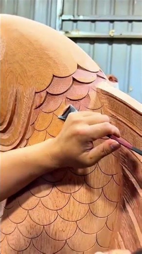 Carving fish scale patterns on a wooden sculpture using a sharp chisel to create artistic textures