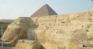 panorama of the sphinx statue in cairo, against the backdrop of the pyramids, camera movement from tail to face. Side view, slow motion, clear day, no people, doves on the head of the statue.