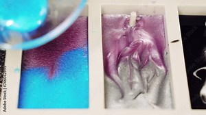 Mixing pink and blue epoxy resin in silicone mold on working surface, colours pigments with brilliant shades being mixed for creating exclusive natural pattern sample, innovative method of furniture Stock Video