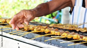 Video shows pork satay skewers being grilled on a hot charcoal grill, Thailand.