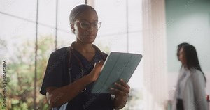 African Healthcare Nurse Using Tablet Computer for Day-to-Day Hospital Operations. Beautiful Young Clinic Professional Doing Online Medical Work in Modern Office in Public Health Care Facility