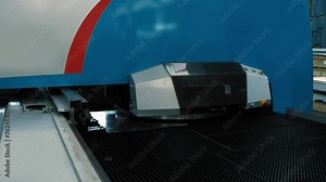 Automated punching machine on a production line. Automated punching machine makes holes in the metal sheet. Automated machine punching holes in the steel material. Manufacturing Equipment