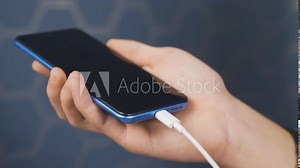 Attaching a charging adapter to phone.