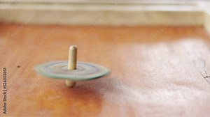 Close up and slow motion 4K of spinning top on board game with high speed rotation and and blur motion shows the retro or vintage game for entertaining kid or child in leisure time.