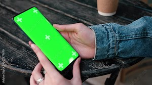 Lviv, Ukraine - May 6, 2022: Close up of a woman's hand holding a mobile telephone with a vertical green screen outside chroma key smartphone technology cell phone street touch message display hand