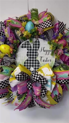 This beautiful Easter Egg Wreath is made with black and white deco mesh, and pastel curls. It measures 20 x 20 x 10 inches. It’s accented with Easter Eggs that are resting in a bed of flowers and greenery. A big multilayered bow tops off the wreath! The wreath has the cutest metal sign with a buffalo check bunny and the word Happy Easter in a beautiful cursive. The bunny is standing in a bed of grass with Easter eggs around him waiting to be hid! You will be the envy of your neighbourhood with t