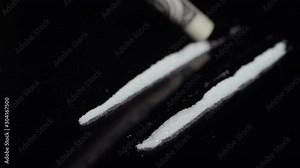 Close-up of lines of white cocaine getting snorted up with a dollar bill on a mirrored surface