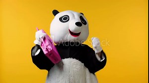 person in panda bear costume dancing with boombox isolated on yellow