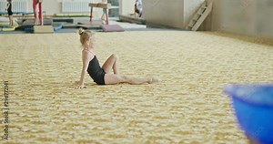 Little girl falling after handstand, performing handstand with split and falling on carpet while exercising during training in professional gym