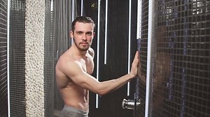 Young sportsman is taking a shower after jogging. Touch hair. Slow motion