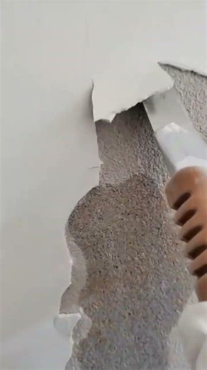 worker scraping old paint layer from wall surface using scraper