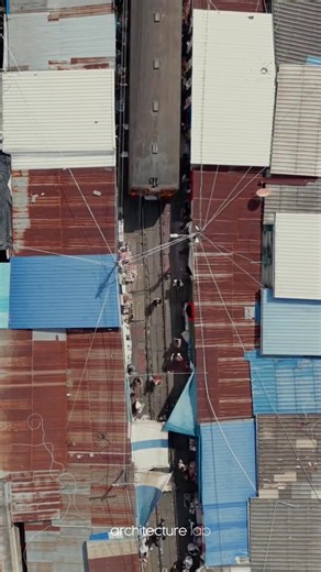 A railway market in Thailand operates directly on active train tracks, where commerce and infrastructure overlap without separation. Vendors arrange fruit and vegetables along the rails, occupying the same linear corridor used by passing trains. When a train approaches, stalls are folded back within seconds, clearing the track before resuming operation immediately after. The market functions through routine coordination rather than fixed boundaries. Movement, timing, and collective awareness rep