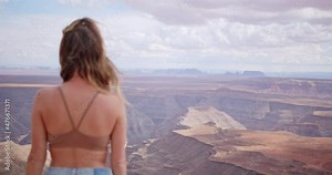 Young female model standing at the edge of a cliff overlooking a canyon in a remote area in the western United States