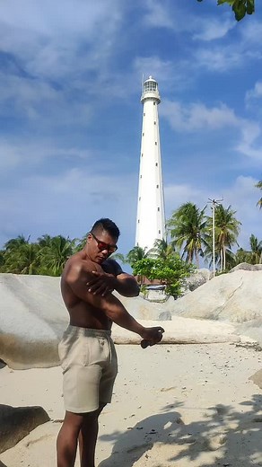 Muscular Man at Scenic Beach with Lighthouse
