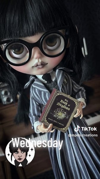 🖤NOW AVAILABLE🖤 (Shop link in bio) Meet my Addams Family series inspired Blythe, Wednesday! She’s dressed in her school uniform and ready for some spooky adventures. Wednesday comes with all of the following (as seen in photos): -Hand-made 5 piece school uniform by RabbittInTheMoon on Etsy -1 set zip-up, knee high boots -1 set lace underwear -1 set metal-framed, cat-eye glasses -1 handmade braid headband -1 functional spooky book (**MAY NOT BE EXACTLY AS PICTURED) -1 fully articulated 3.1 mode